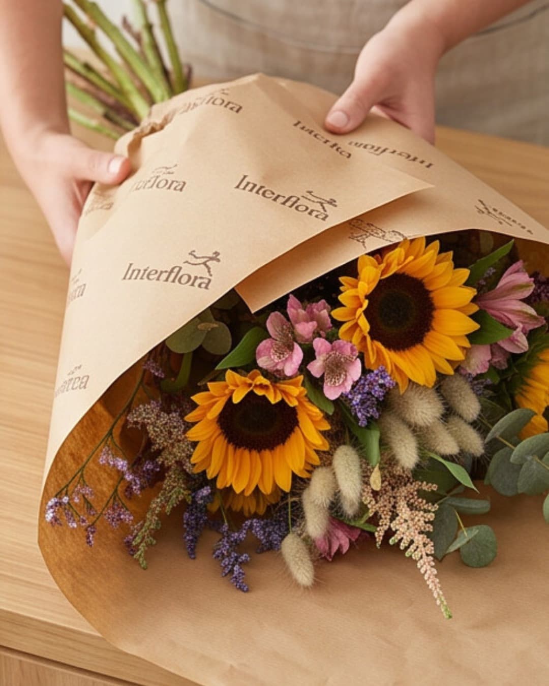 Ramo de girasoles y flores de temporada envuelto en papel Interflora en la floristería de Vigo
